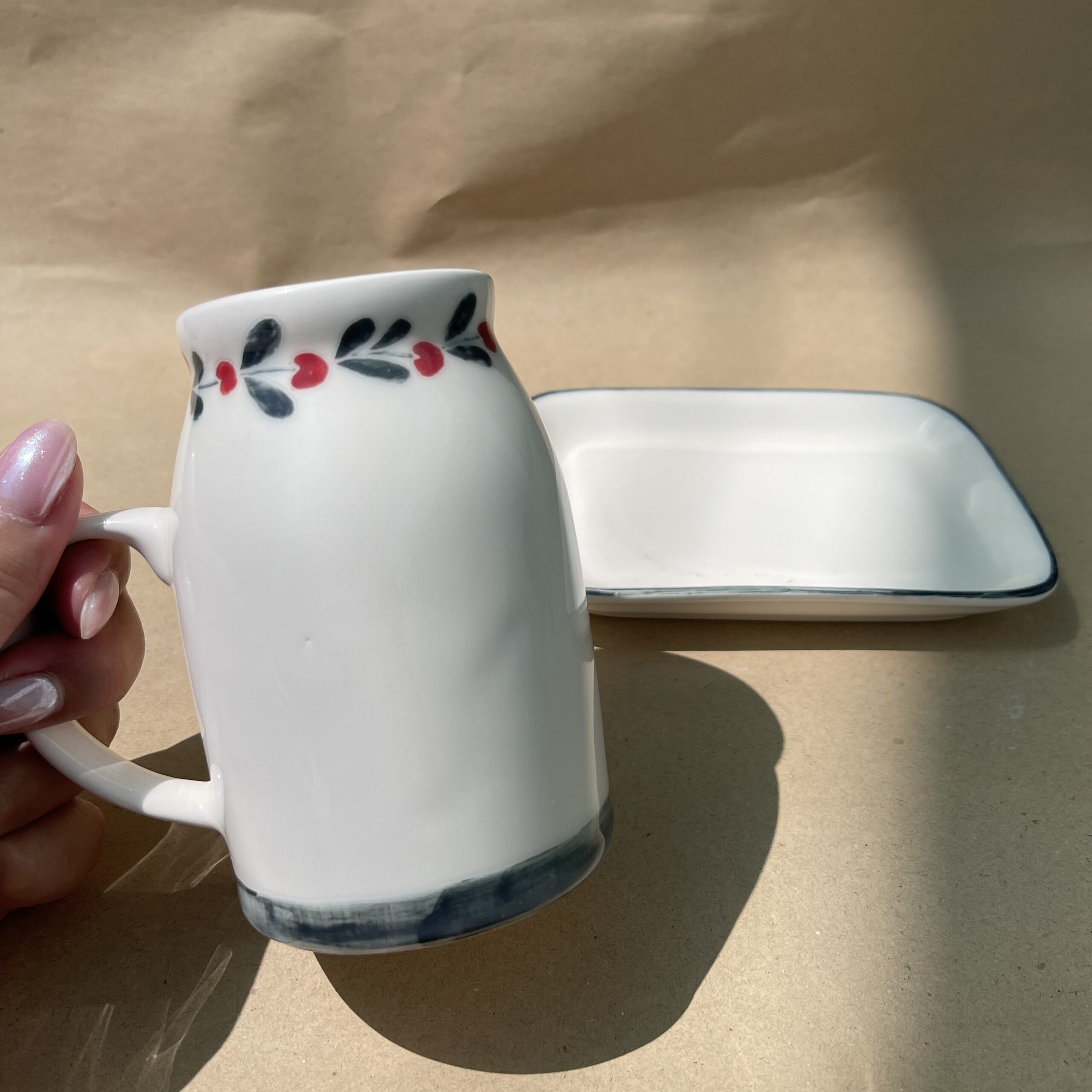 Keramik-Tasse und Untertassenset, handbemalt mit Blüten- und Blattmuster am Rand