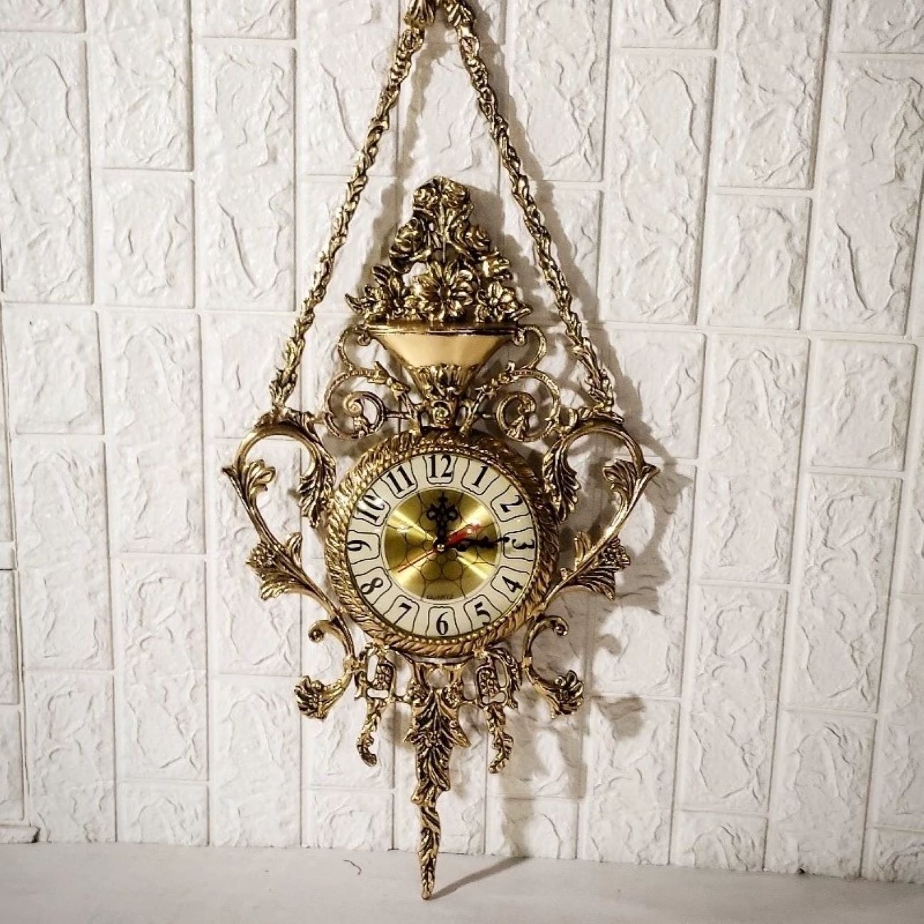Charmante Messing-Wanduhr mit dekorativen Blumenakzenten und Hängeelement