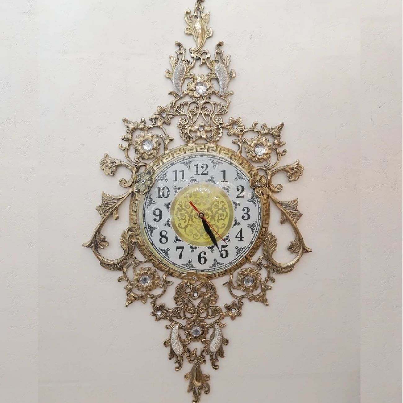 Charmante Messing-Wanduhr mit dekorativen Blumenakzenten und Hängeelement